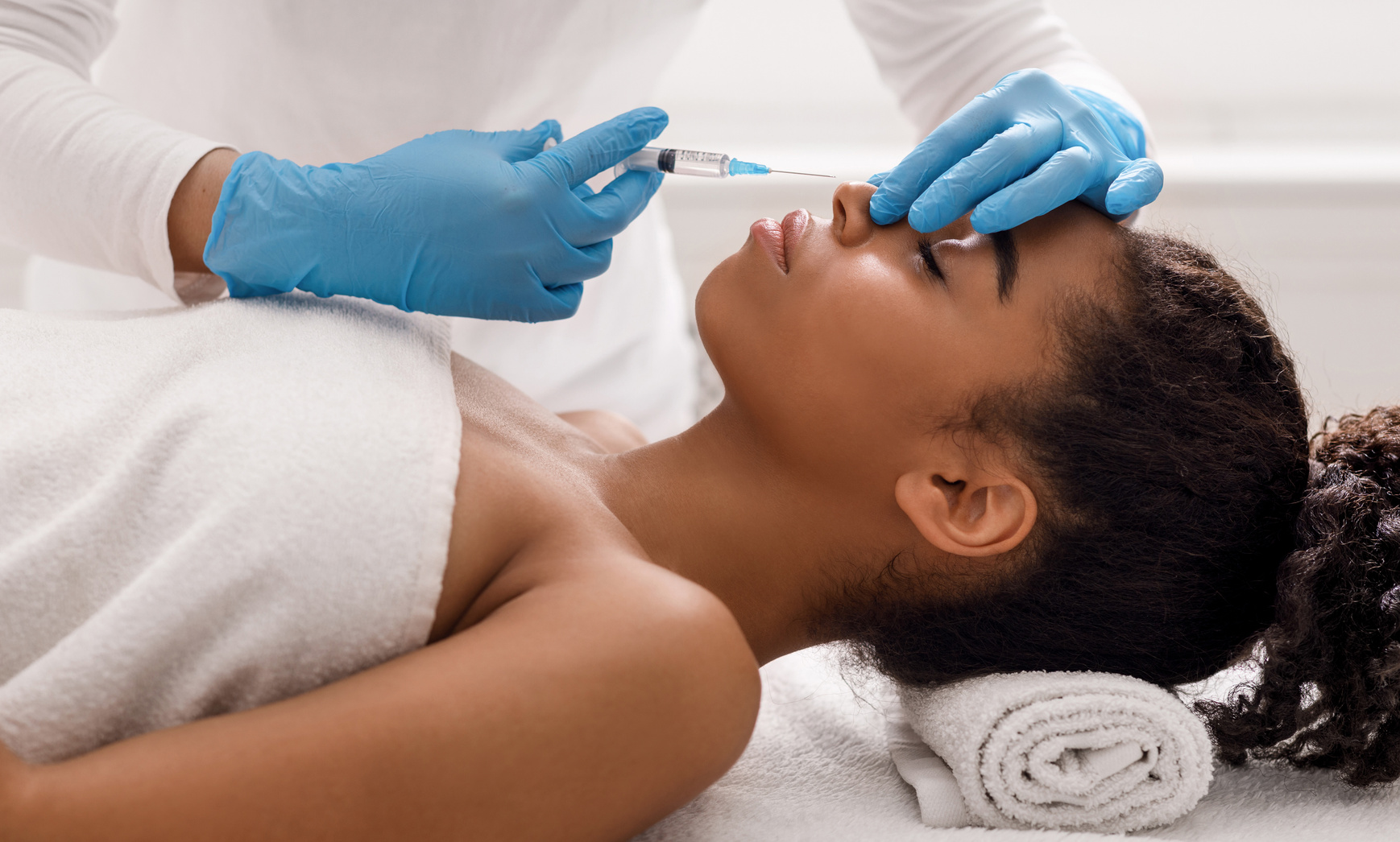 Black lady receiving beauty injections for nose zone