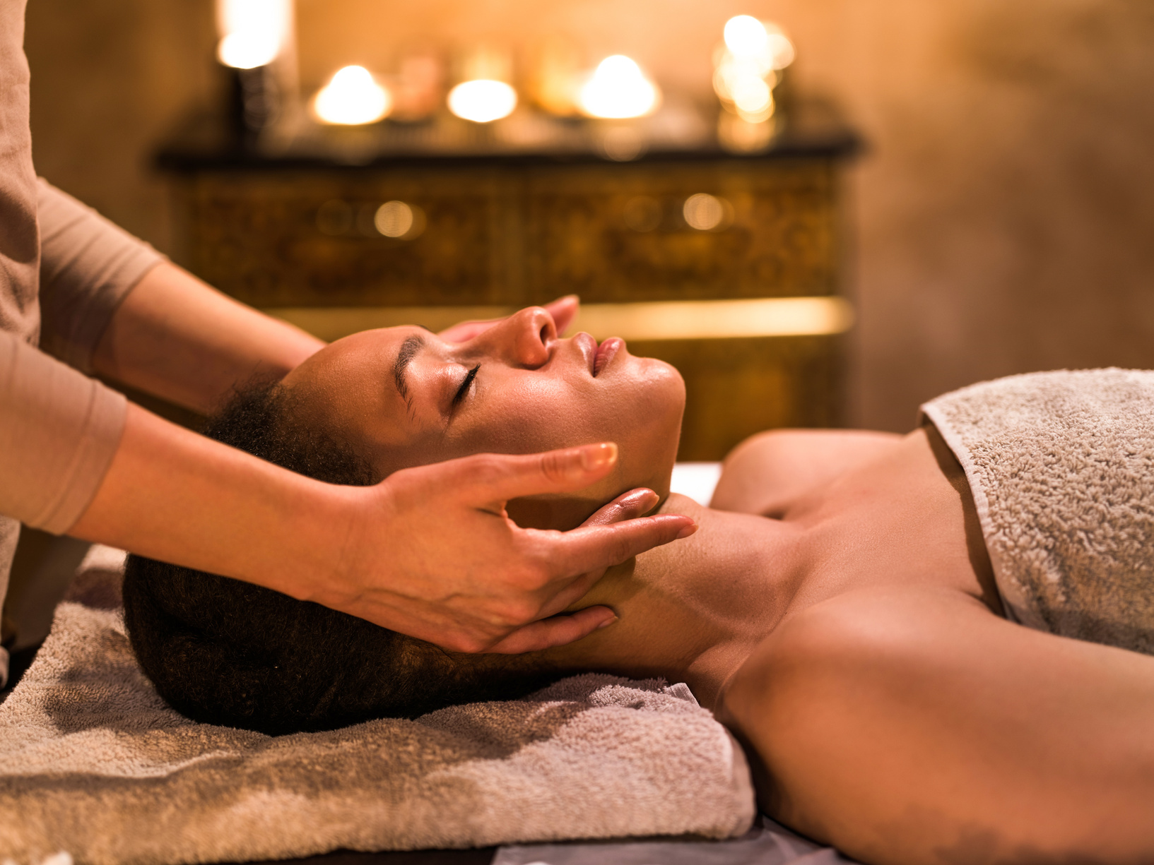Relaxed black woman having facial massage at the spa.